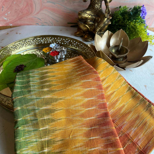 Pochampalli fabric in green and yellow with a bold zigzag pattern, handwoven from a cotton blend, displayed with traditional decor.
