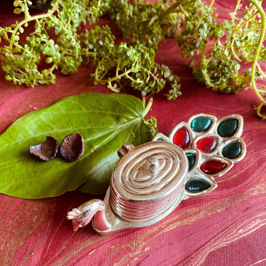 Silver kumkum box designed as a peacock with multicolor accents on its feathers, perfect for pooja and festive decor.