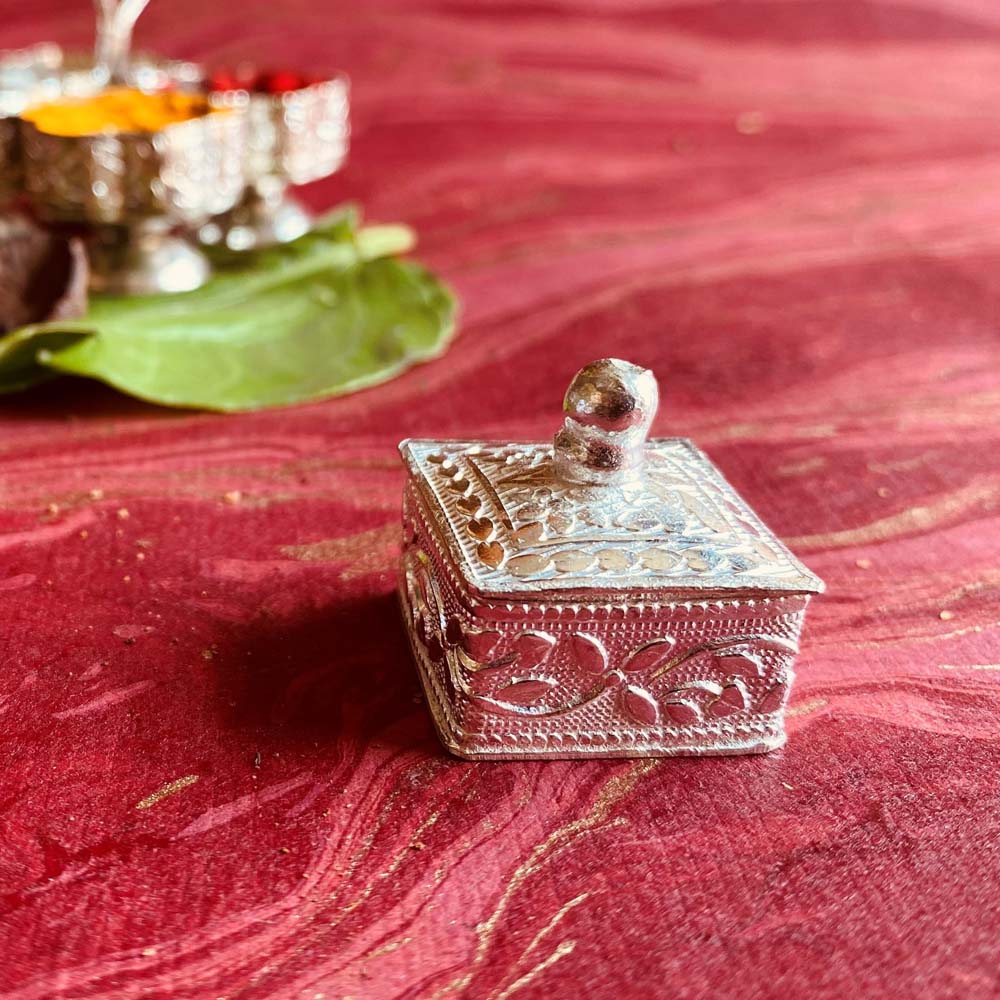 Square silver kumkum box with intricate floral engravings, perfect for pooja rituals and gifting.