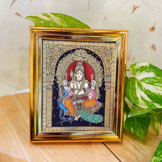 Tanjore-style artwork of Lord Murugan seated on a peacock, set against a black backdrop with intricate detailing and enclosed in a golden frame.