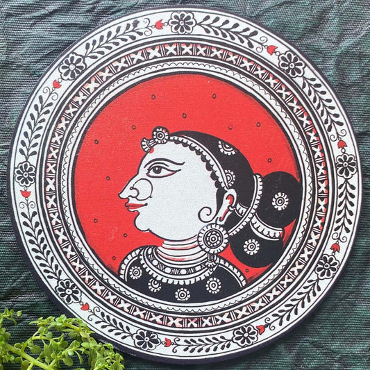 Handmade Madhubani art coaster with a portrait of a tribal woman in a bold red, black, and white design.