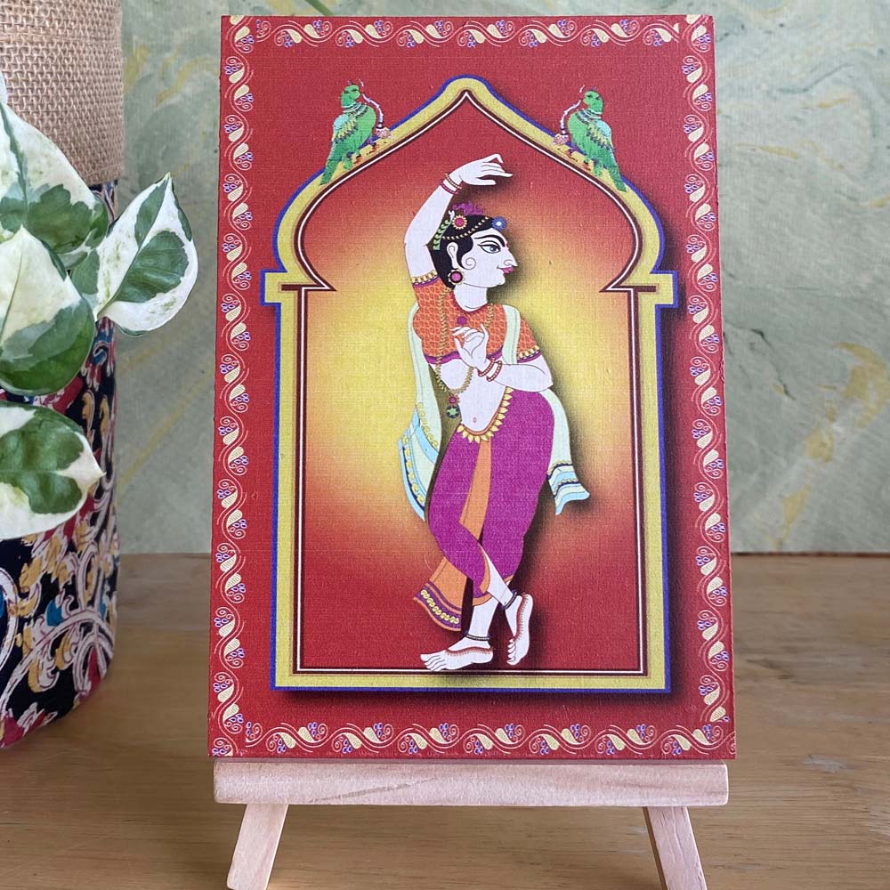 Decorative artwork of a village lady in vibrant pink and yellow attire, framed by a minaret-style arch with intricate detailing, displayed on a wooden easel.