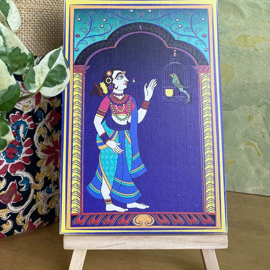 Decorative artwork of a lady admiring a parrot in a cage, framed by a minaret-style arch with intricate details, displayed on a wooden easel.