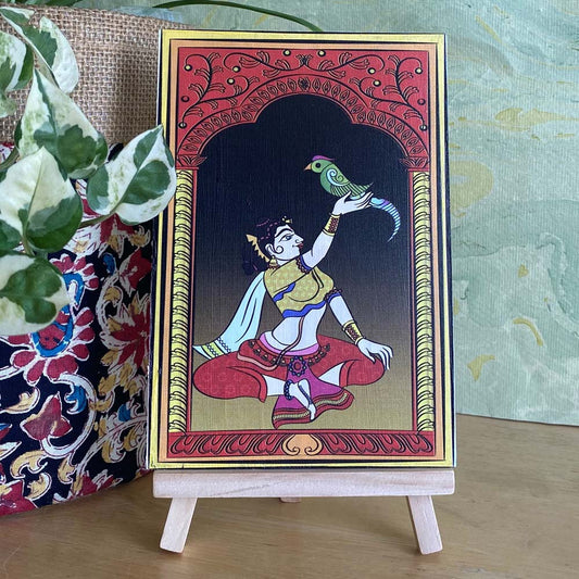 Decorative artwork of a lady holding a parrot, framed by a minaret-style arch, featuring intricate designs and vibrant colors, displayed on a wooden easel.