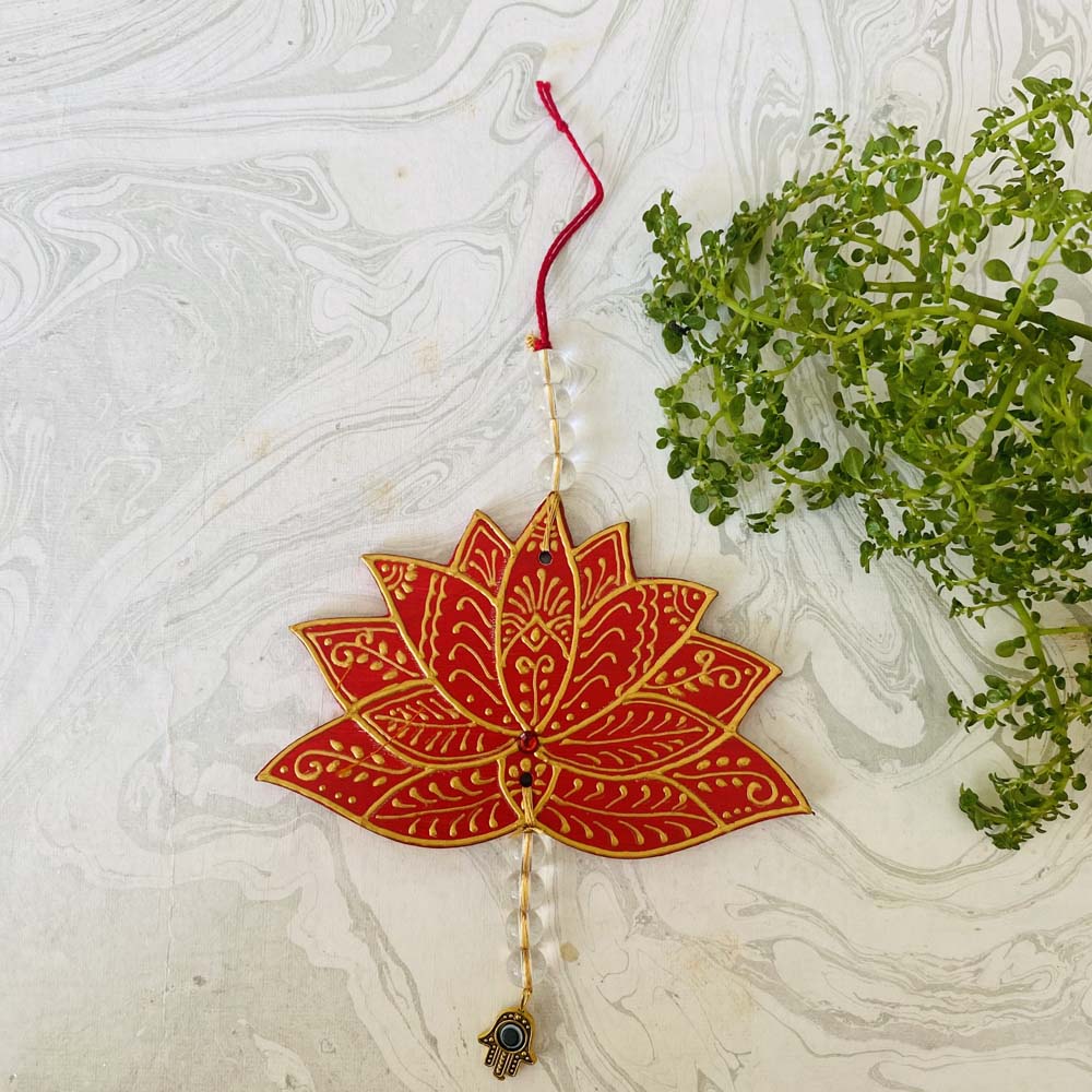 Handcrafted red lotus-shaped hanging ornament with gold detailing, beads, and an evil eye charm, ideal for walls and meditation spaces.