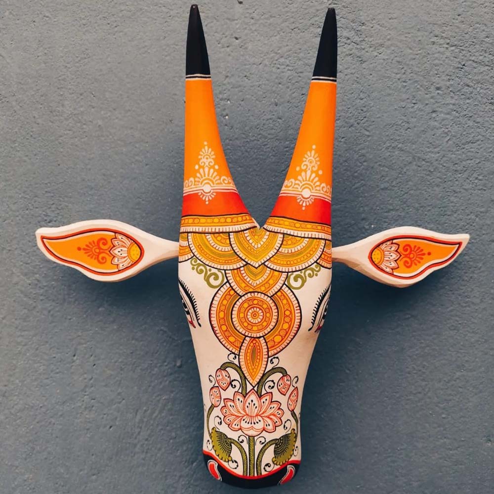 Hand-painted decorative wooden cow head with intricate Indian folk art design in vibrant orange and blue tones.
