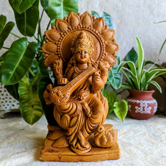 Handcrafted terracotta Navarathri Golu doll of Goddess Saraswathi holding a veena with a swan beside her, finished in earthy tones.