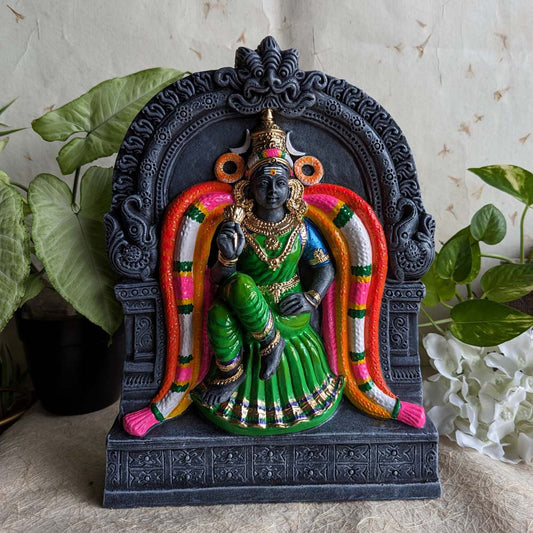 Kamalambal (Kamalambigai) Golu doll seated within a black temple frame, dressed in a green saree and adorned with vibrant garlands and ornaments.