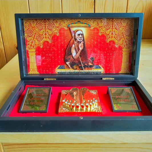 Grand Mahaperiyava Padhuka set in a black-framed box with golden holy feet, vibrant framed artwork of Mahaperiyava, and engraved plaques on a red velvet background.