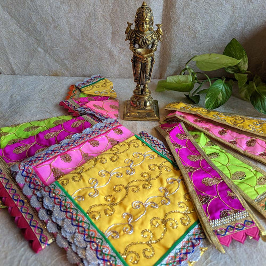 Handcrafted Sai Vastra set in vibrant colors with intricate embroidery and sequin work, displayed alongside a brass Sai Baba idol.