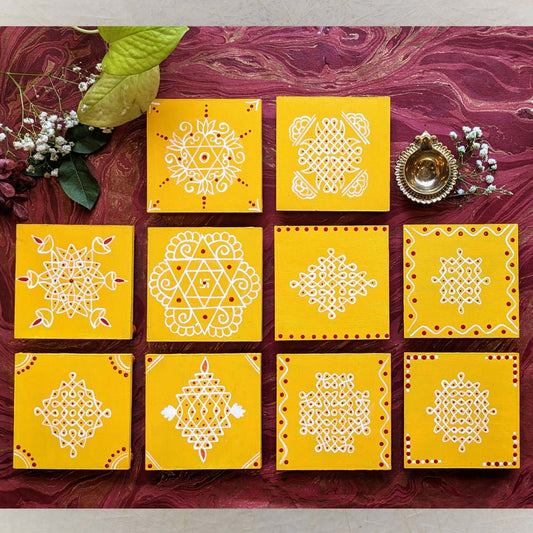 Bright yellow wooden manai set with hand-painted traditional kolam designs in white and red, displayed on a decorative background.