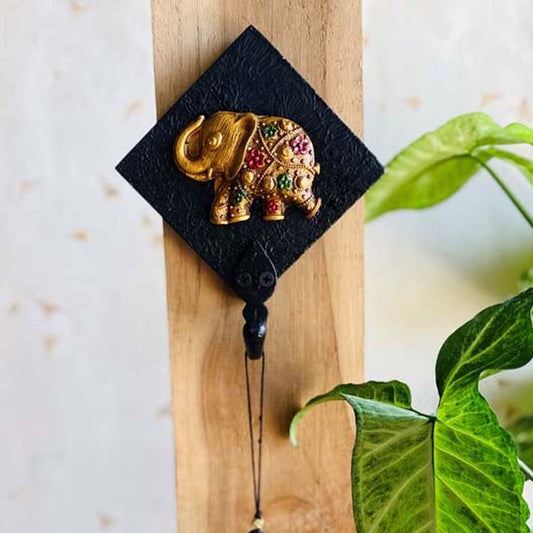 Handcrafted black key holder with a golden elephant motif and colorful embellishments, mounted on wood.