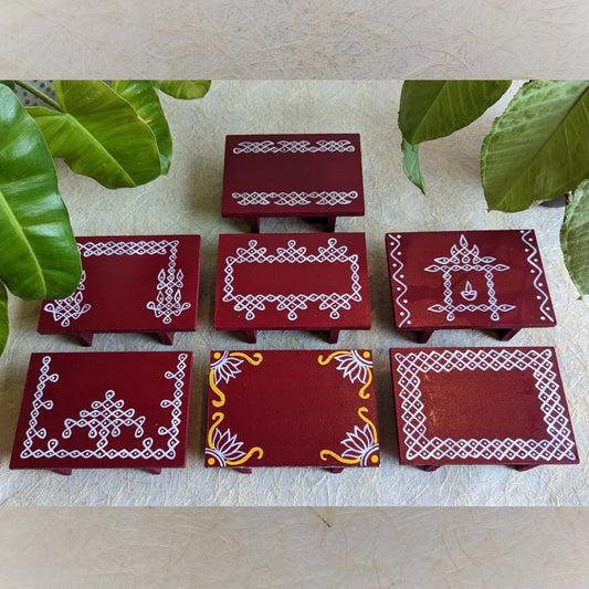 Maroon wooden pooja platform with intricate white Kolam patterns, perfect for rituals and decor.