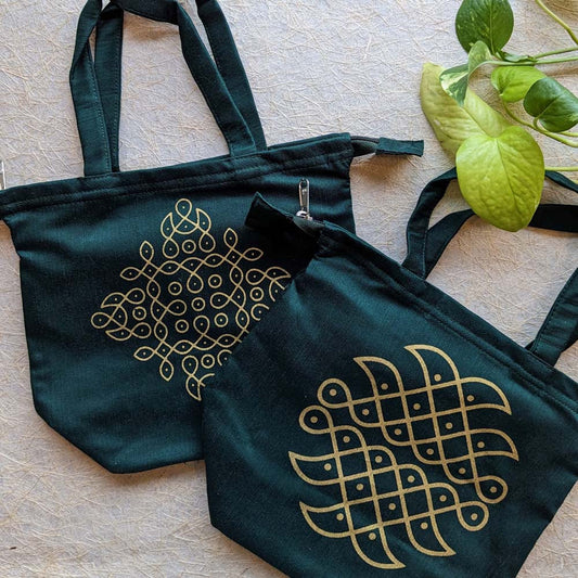 Green cotton tote bags featuring golden kolam designs, displayed on a textured background with green leaves.