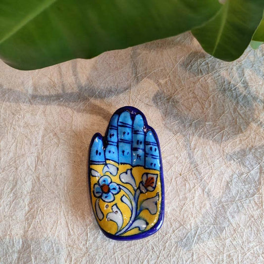 Handcrafted ceramic incense holder in a hand shape with blue and yellow floral design, ideal for home decor and spiritual use.
