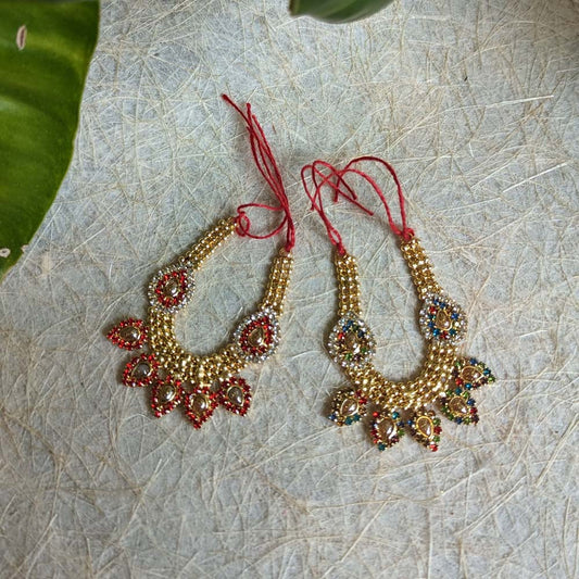 A pair of 4-inch traditional beaded fabric necklaces with multicolor stone embellishments and red adjustable threads, displayed on a textured surface.