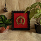 Brass Goddess Gauri wall décor with ornate arch mounted on red velvet background in a black wooden frame.
