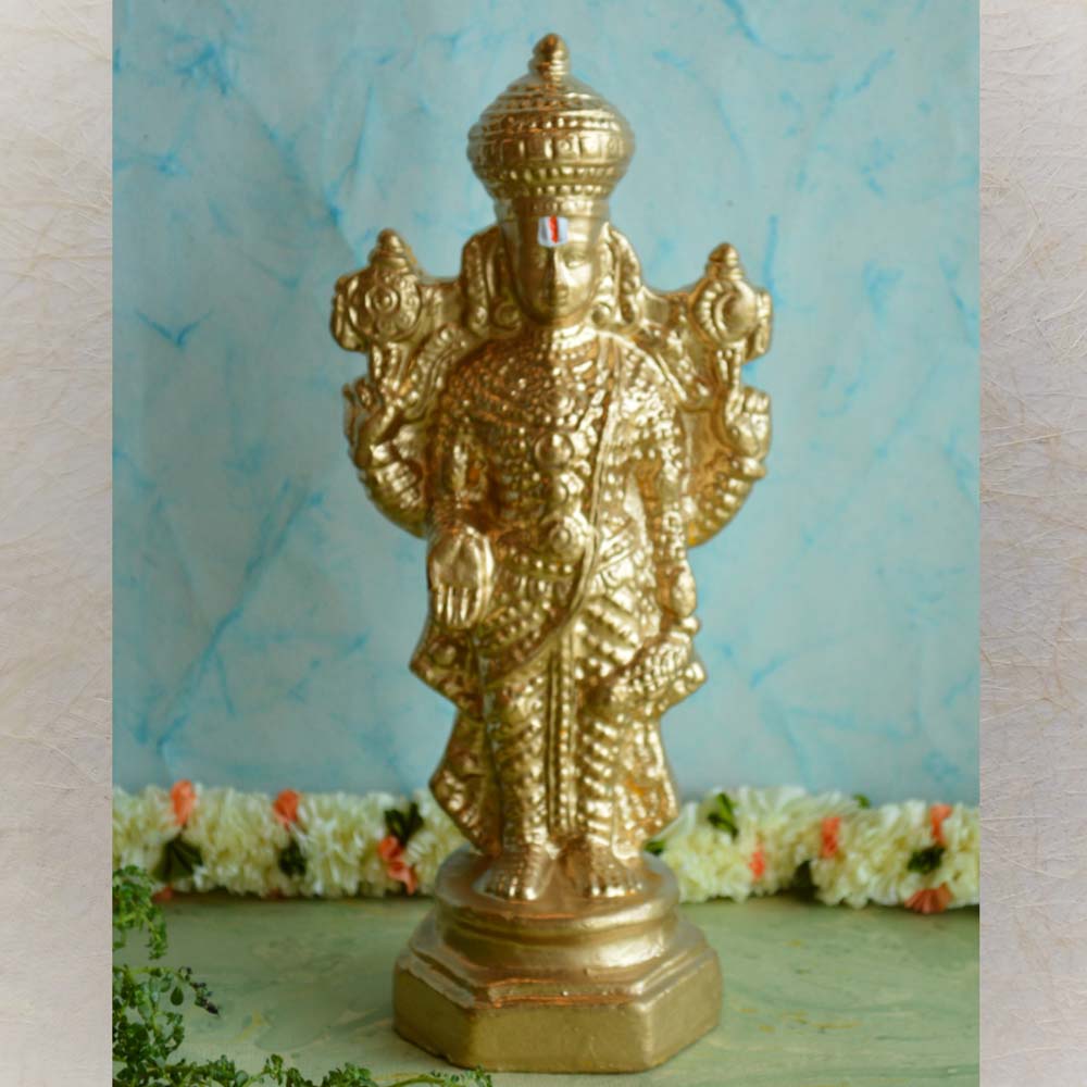 Handcrafted golden idol of Vairamudi Perumal, detailed with intricate carvings, representing the Vairamudi Sevai tradition, set against a decorative background.